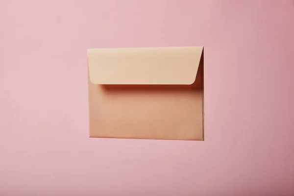 Бежевый и пустой конверт на розовом фоне с копировальным местом — стоковое фото