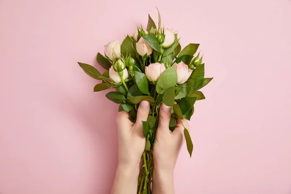 Partial view of female hands with beautiful bouquet of roses on pink — Stock Photo