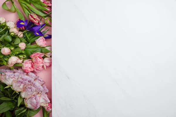 Vista superior de hermosas rosas frescas, tulipanes e iris sobre fondo rosa y blanco - foto de stock