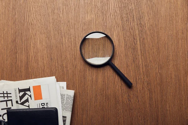 Top view of newspaper near magnifier on wooden surface — Stock Photo