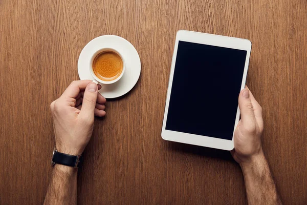 Vista ritagliata di uomo in possesso di tablet digitale con schermo bianco e tazza di caffè — Foto stock