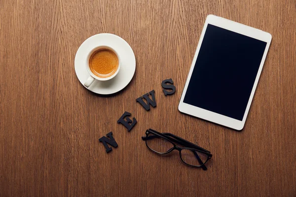 Vue du dessus de la tablette numérique avec écran blanc près de nouvelles lettrage, tasse de café et verres — Photo de stock