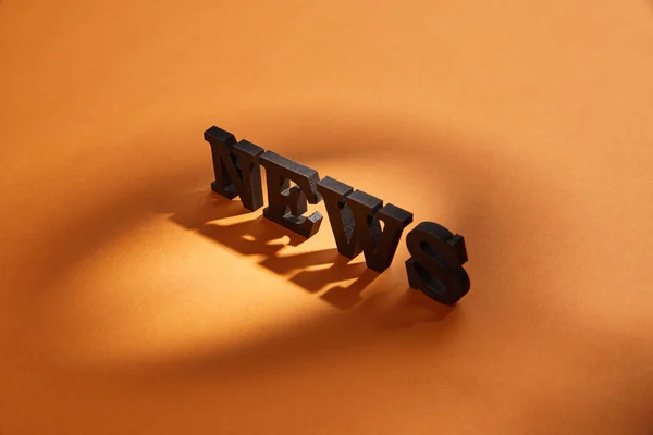 News lettering with copy space and shadows on orange — Stock Photo