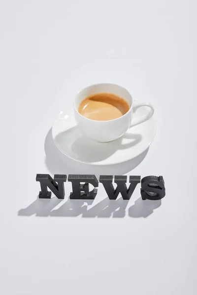 Черные новости с чашечкой кофе на белом — стоковое фото