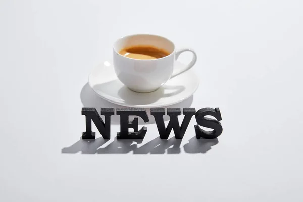 Черные новости с чашечкой кофе на белом — стоковое фото