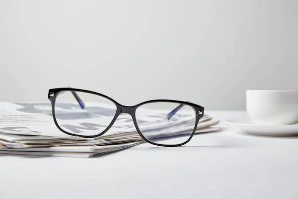 Foyer sélectif de lunettes près de journal d'affaires et tasse sur blanc — Photo de stock