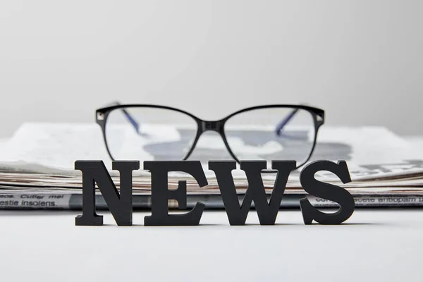 Enfoque selectivo de las letras de noticias cerca de gafas y periódico en blanco - foto de stock