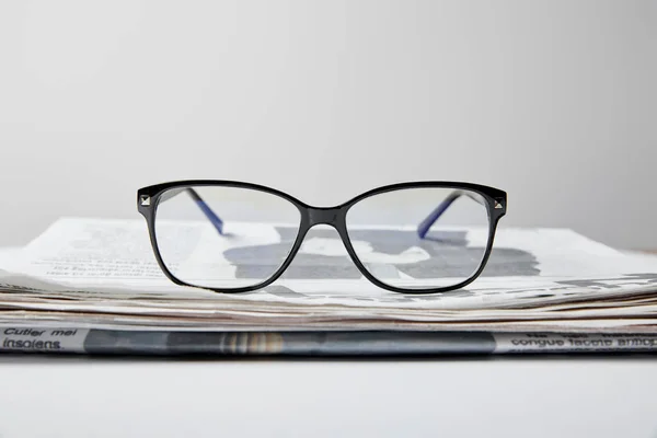 Foyer sélectif de lunettes près du journal sur blanc — Photo de stock