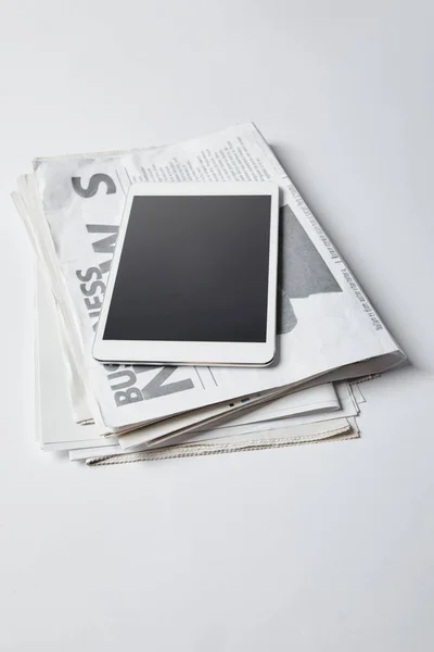 Digital tablet with blank screen on business newspapers on white — Stock Photo