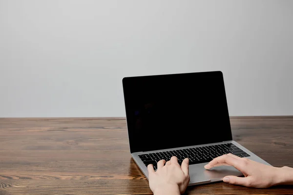 Cropped view of woman using laptop on wooden surface — Stock Photo
