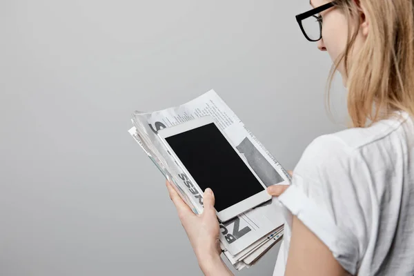 Обрізаний вид жінки в окулярах, що тримає цифровий планшет з порожнім екраном і газетами ізольовані на сірому — стокове фото