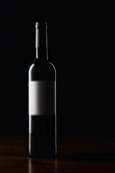 Wine bottle with blank label on wooden surface — Stock Photo