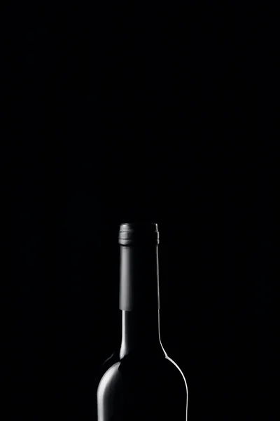 Glass wine bottle in darkness isolated on black — Stock Photo