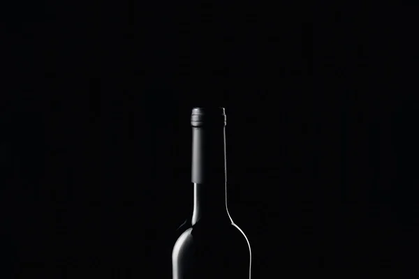 Glass wine bottle in darkness isolated on black — Stock Photo