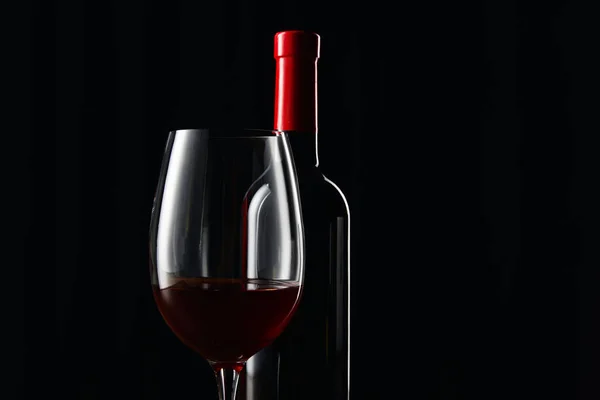 Bottle and glass of red wine isolated on black — Stock Photo