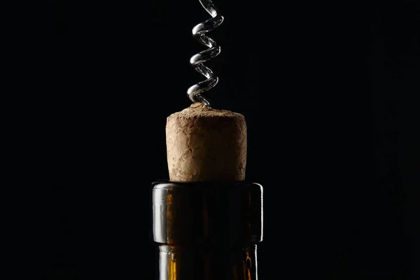 Close up view of glass wine bottle with wooden cork and corkscrew isolated on black — Stock Photo