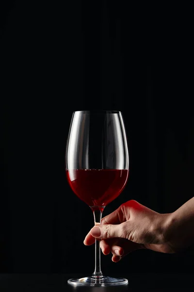 Partial view of woman holding wine glass with red wine isolated on black — Stock Photo