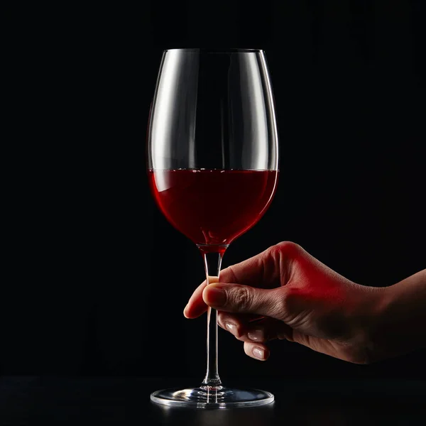 Vue recadrée d'une femme tenant un verre à vin avec du vin rouge isolé sur noir — Photo de stock