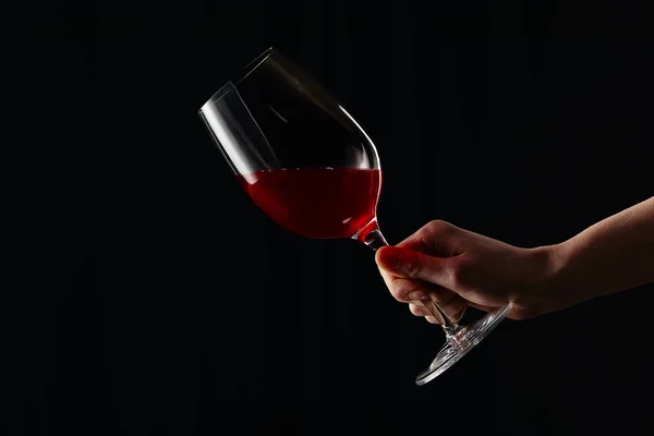 Partial view of girl holding wine glass with red wine isolated on black — Stock Photo