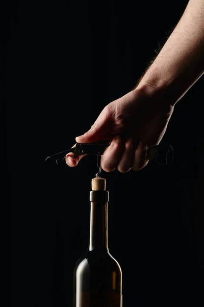 Abgeschnittene Ansicht eines Mannes, der eine Weinflasche mit Korkenzieher öffnet, isoliert auf schwarz — Stockfoto