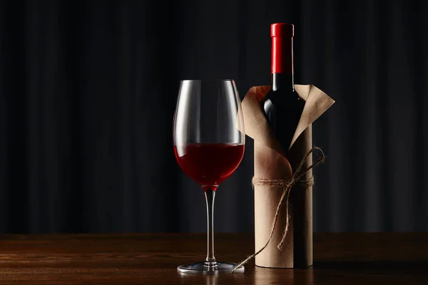 Copa de vino y botella en papel sobre superficie de madera - foto de stock