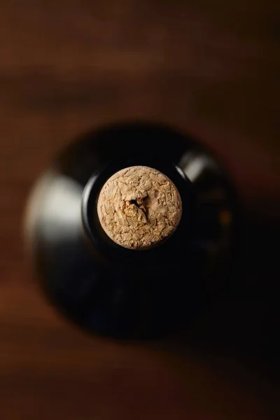 Vue du dessus de la bouteille de vin avec bouchon en bois sur la surface brune — Photo de stock