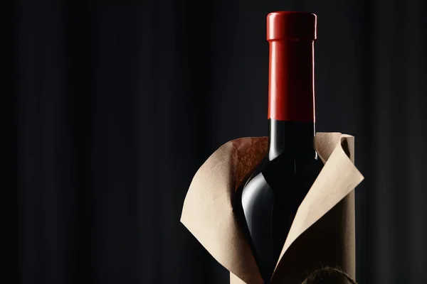 Bouteille de vin en verre dans une enveloppe en papier sur fond sombre — Photo de stock