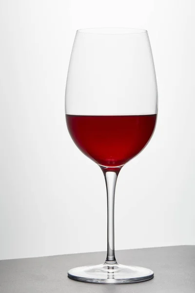 Wine glass with red wine on dark surface on white — Stock Photo