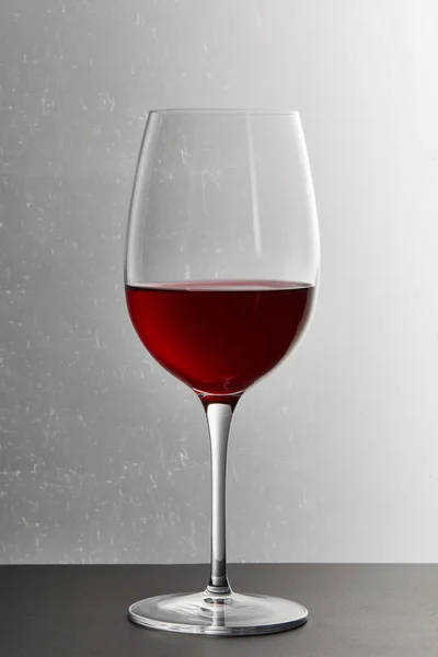 Bicchiere da vino con vino rosso bordeaux su superficie scura su grigio — Foto stock