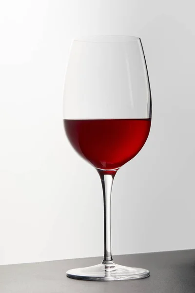 Wine glass with red wine on dark surface on white — Stock Photo