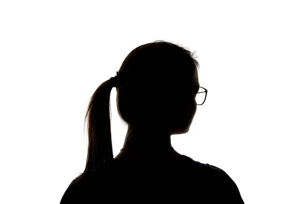 Silhouette eines Mädchens mit Brille und Pferdeschwanz, das isoliert auf weißem Grund wegschaut — Stockfoto