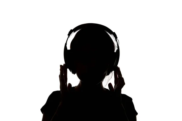 Silueta de chica en auriculares escuchando música en auriculares aislados en blanco - foto de stock