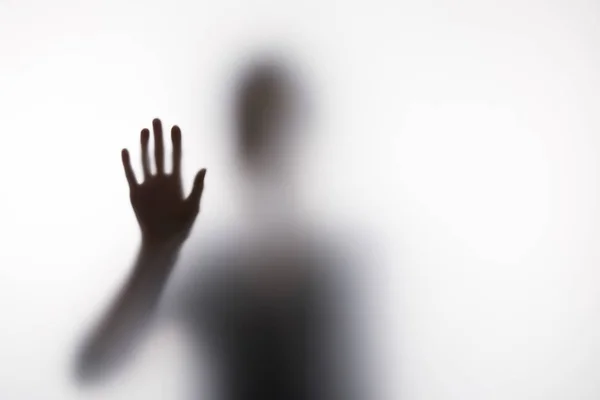 Silhouette sfocata di persona che tocca il vetro con mano — Foto stock