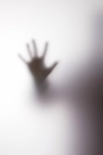 Blurry silhouette of person touching glass with hand — Stock Photo