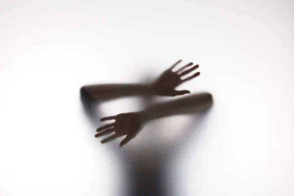 Silhueta desfocada de pessoa tocando vidro com as mãos — Fotografia de Stock