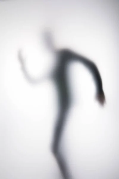 Blurry silhouette of person behind glass on white — Stock Photo