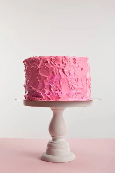 Pink sweet birthday cake on cake stand isolated on grey — Stock Photo