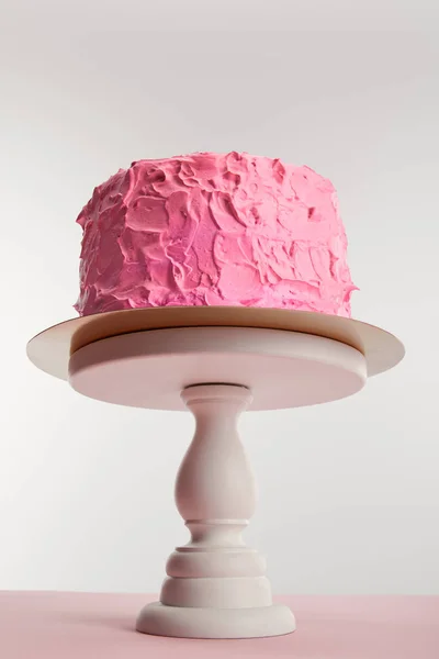 Вид знизу солодкого рожевого торта на день народження на тортній стійці на сірому — стокове фото