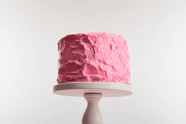 Vista inferior de la torta de cumpleaños de color rosa dulce con crema en pie de pastel aislado en gris - foto de stock
