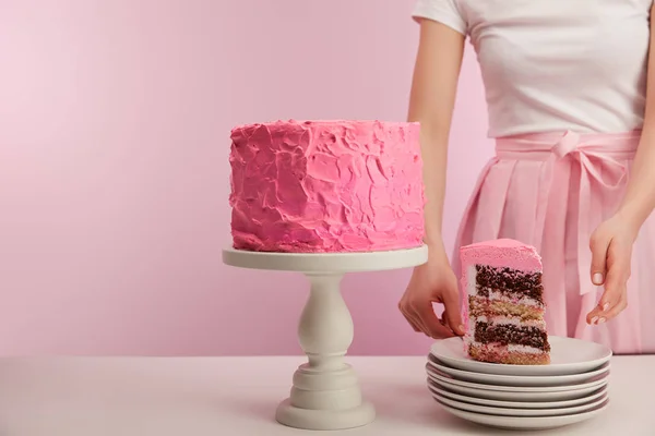 Cropped view of woman standing near piece of sweet birthday cake in white saucer on pink — Stock Photo