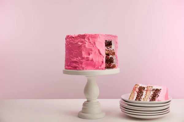 Morceau de gâteau d'anniversaire rose sucré en soucoupe blanche sur rose — Photo de stock