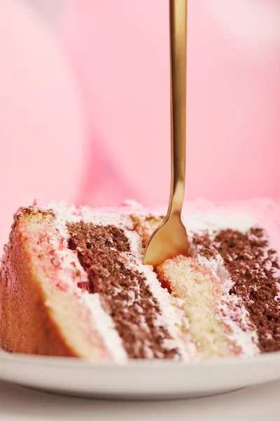 Gros plan de steet morceau de gâteau d'anniversaire savoureux avec fourchette dorée en soucoupe blanche sur rose — Photo de stock