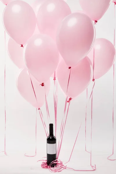 Pink air balloons with wine bottle isolated on white — Stock Photo