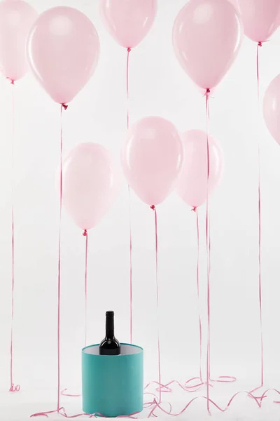 Globos de color rosa con caja de regalo turquesa y botella de vino aislado en blanco — Stock Photo