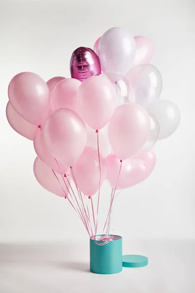 Paquet de ballons roses décoratifs avec boîte cadeau turquoise sur blanc — Photo de stock