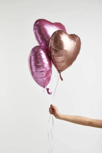 Partial view of girl holding heart-shaped pink air balloons isolated on white with copy space — Stock Photo