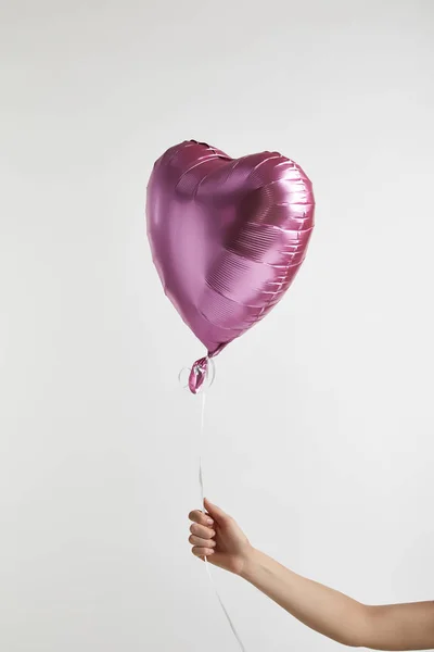 Vista recortada de niña sosteniendo en forma de corazón globo de aire rosa aislado en blanco - foto de stock