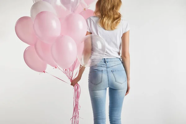 Вид ззаду дівчини в повсякденному одязі, що тримає рожеві повітряні кулі ізольовані на білому — стокове фото