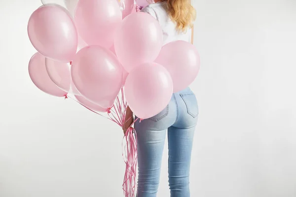 Vista trasera de la niña sosteniendo globos de aire rosa aislados en blanco con espacio de copia - foto de stock