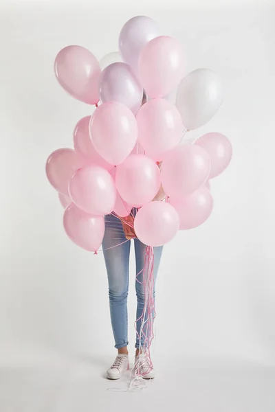 Ragazza che copre il viso con palloncini d'aria rosa isolati su bianco — Foto stock